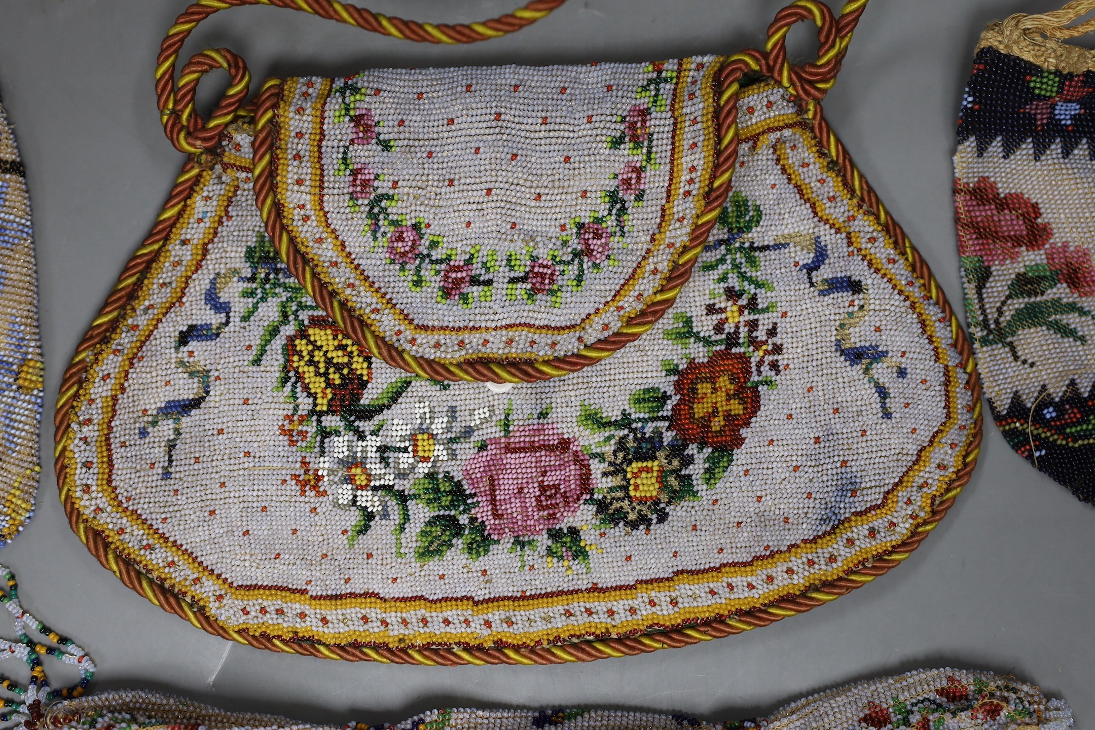 A 19th century shaped floral bead worked bag with corded edging and handle, an unusual bead worked misers purse and two small floral bead bags